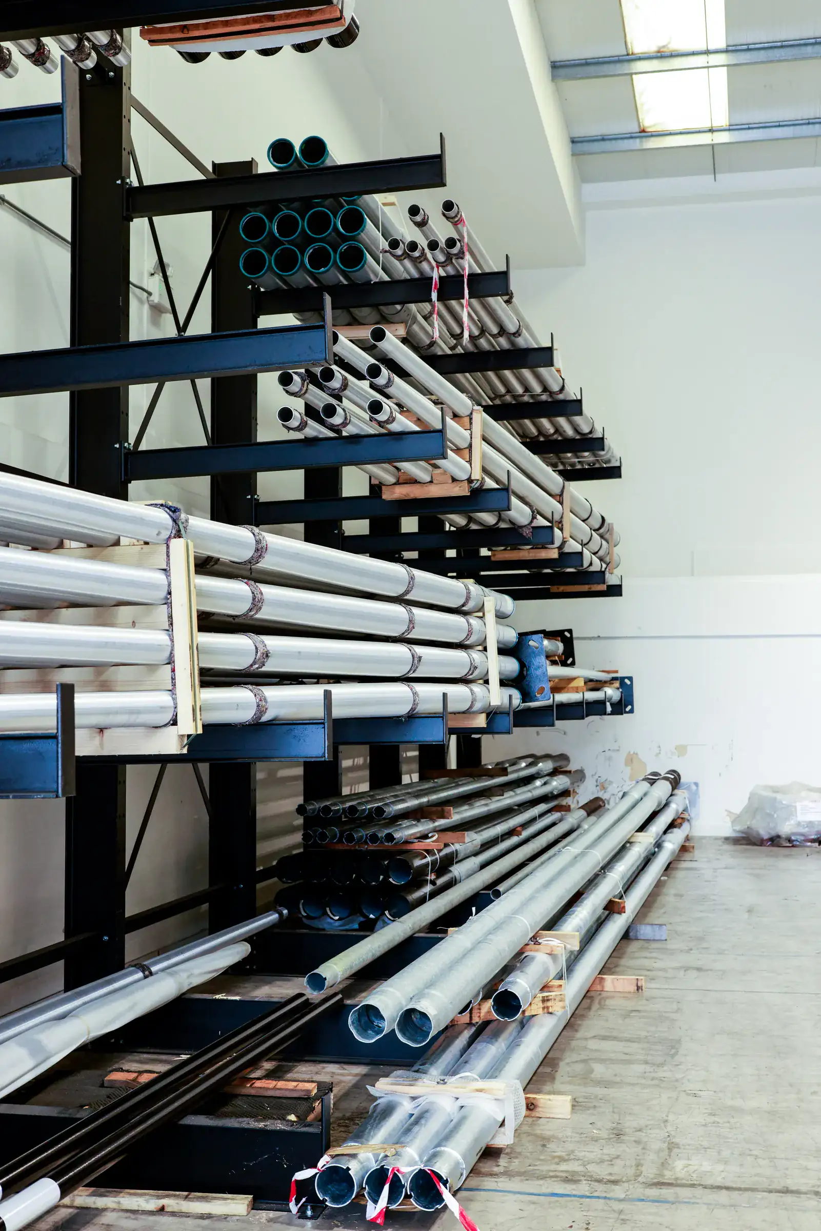Single sided cantilever racking storing long plastic pipe against a wall