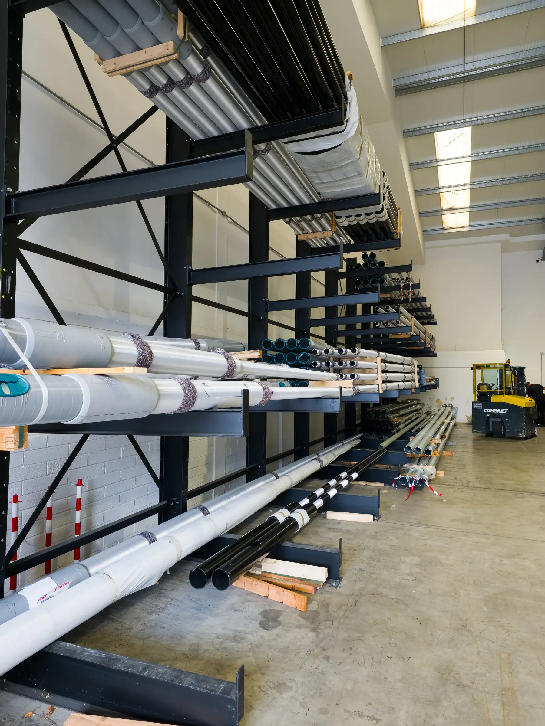 Cantilever racking storing pipe and duct with a forklift in the background