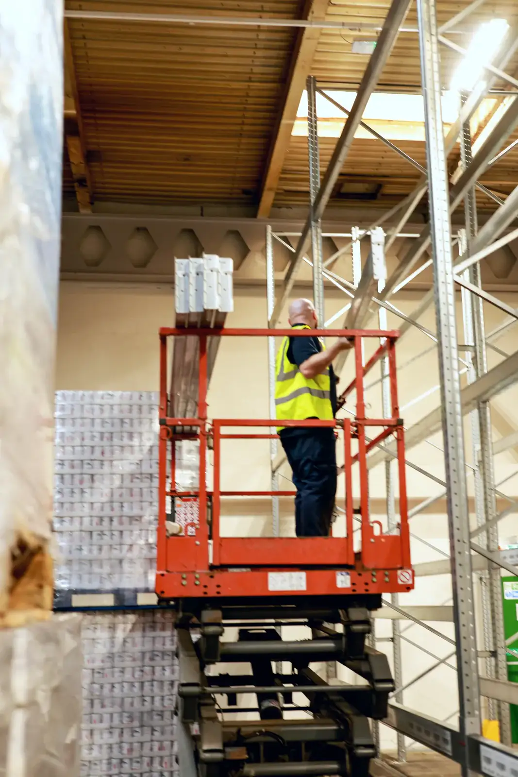 Installer on a scissor lift fitting pallet racking beams