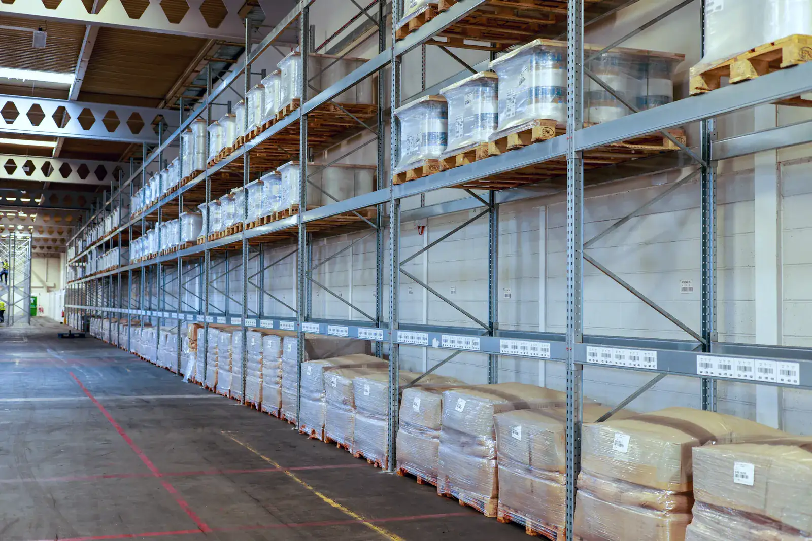 Long run of galvanised pallet racking with bay labels in a distribution warehouse