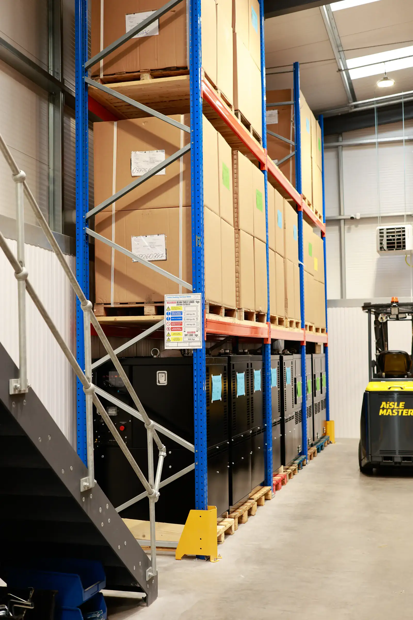 Pallet racking beside a mezzanine staircase with an articulated Aisle-Master truck