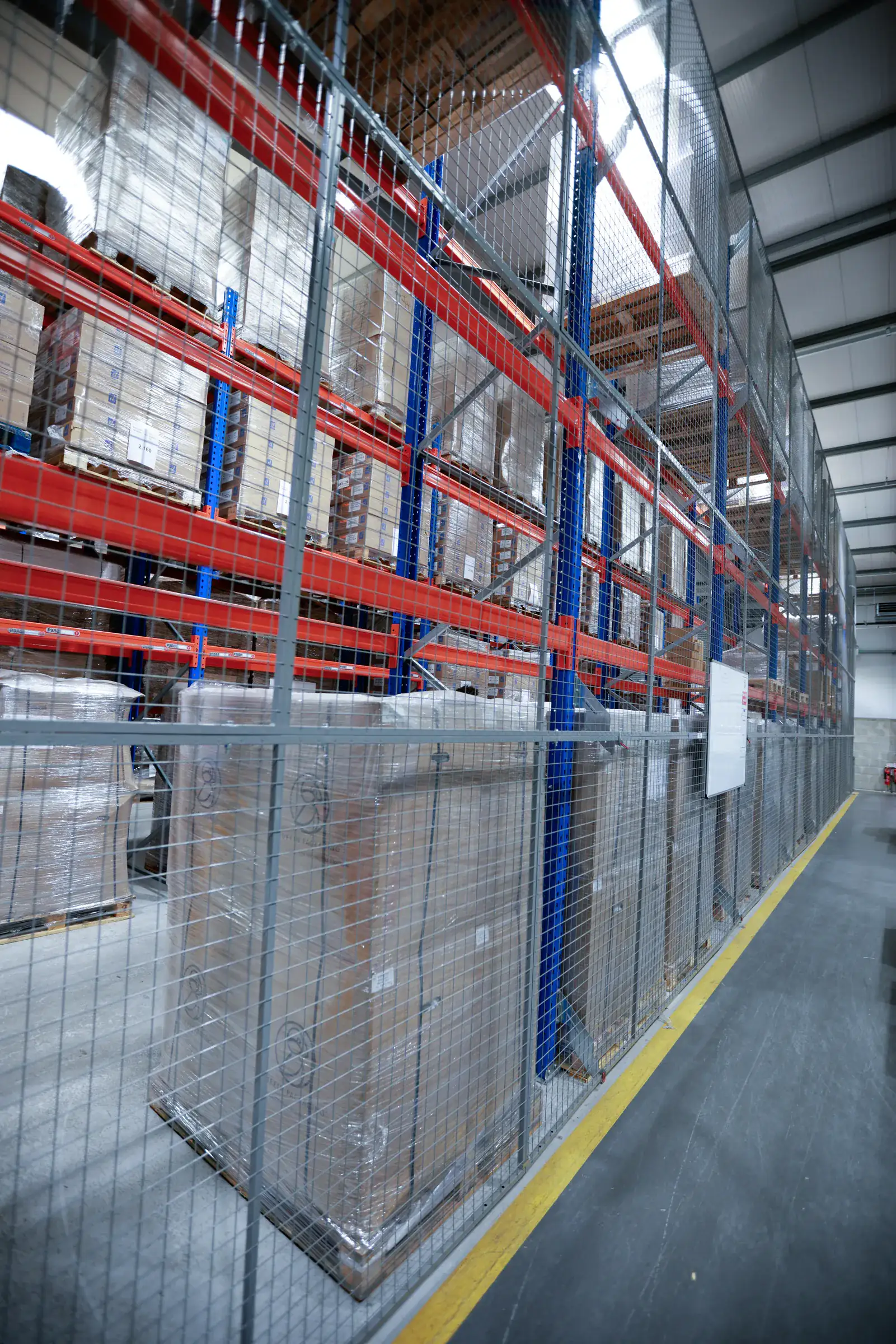 Pallet racking with a mesh cage enclosure along the aisle