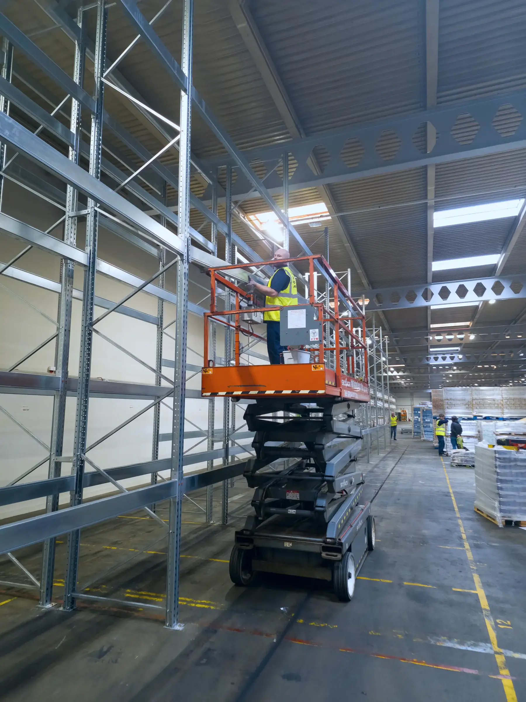 Racking installer on a scissor lift in a new galvanised racking run