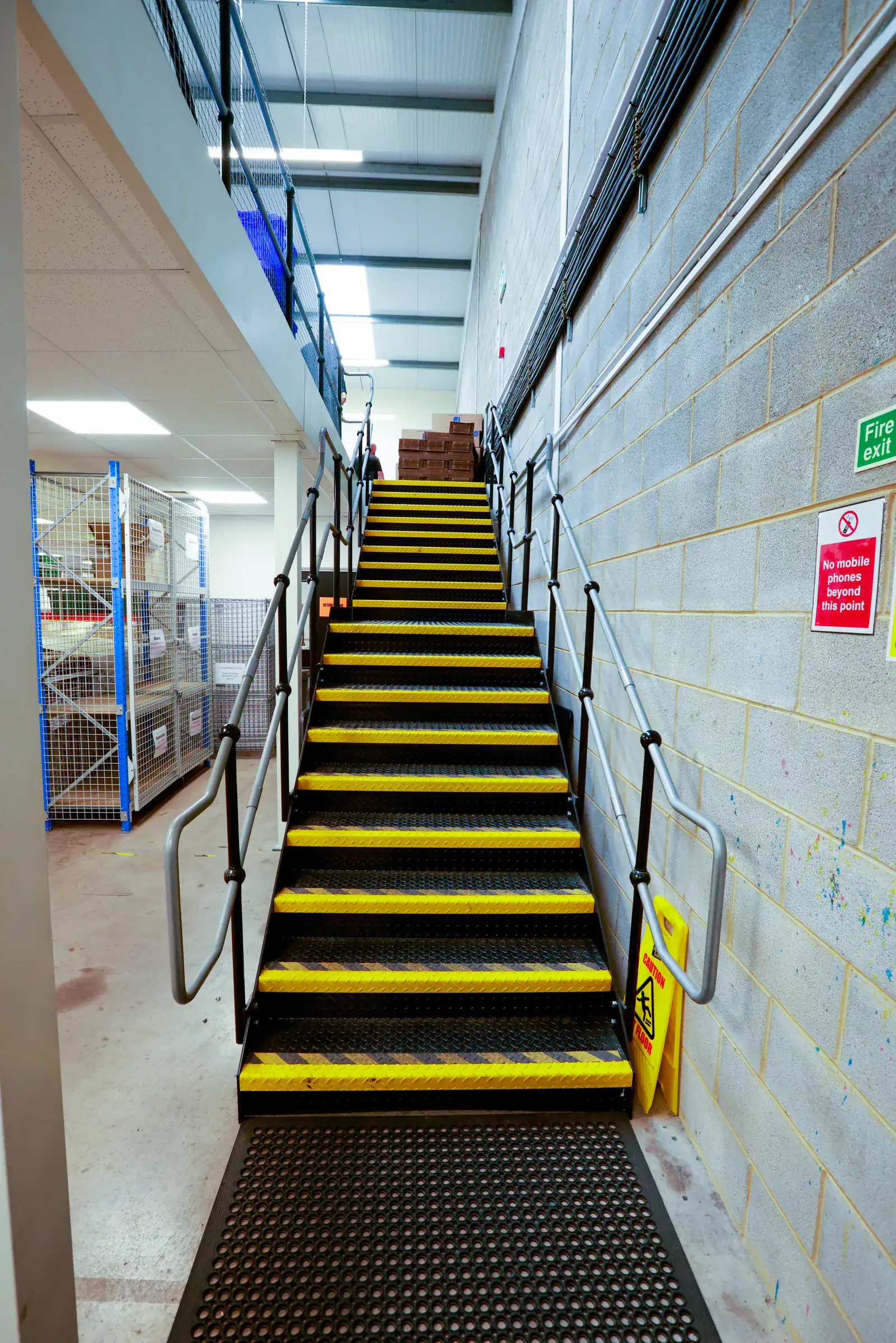 Steel staircase to a mezzanine floor with yellow step nosings