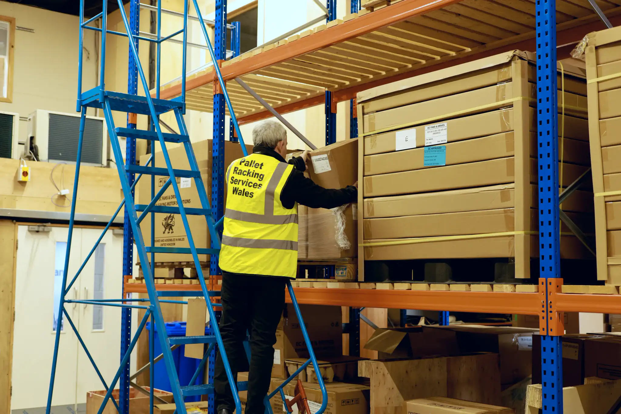 Team member picking stock from mobile safety steps at pallet racking
