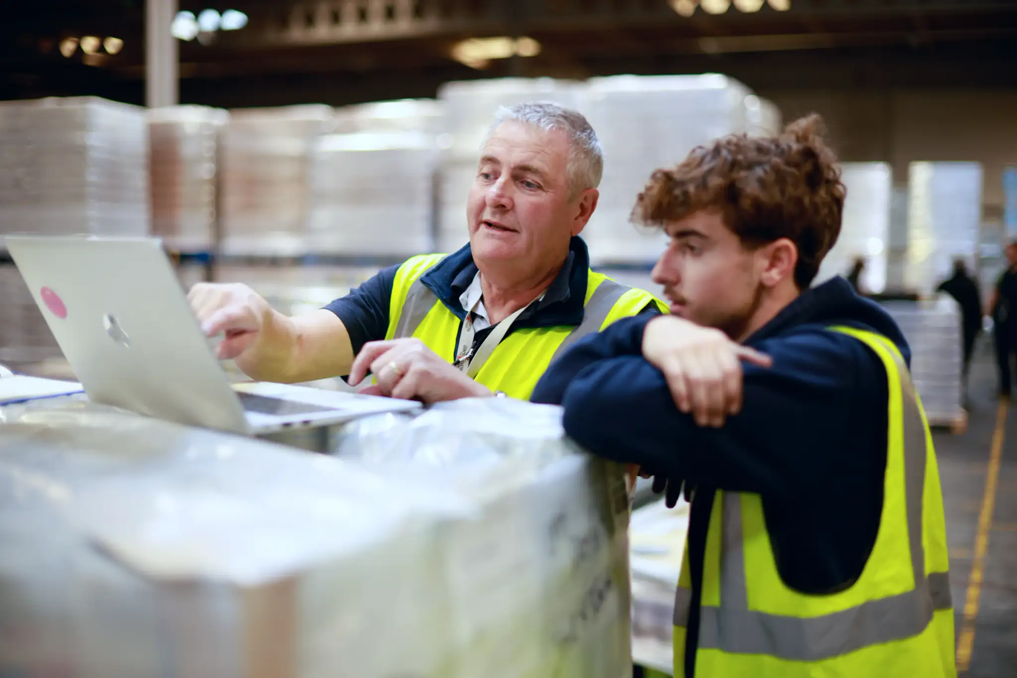 Team planning a racking layout on a laptop in a warehouse